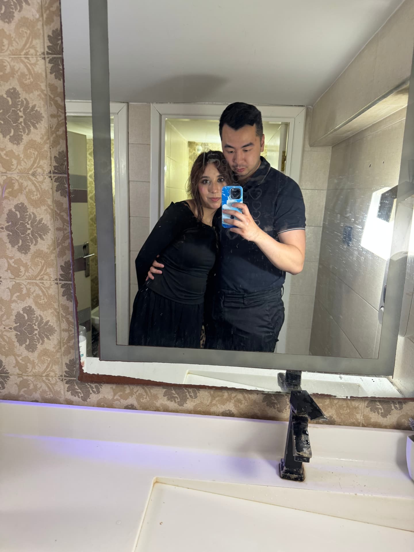 A couple taking a mirror selfie in a bathroom